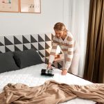 pasando una aspiradora antiácaros por el colchón de la cama